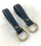 Two black leather key fobs with brass removable D-rings attached
