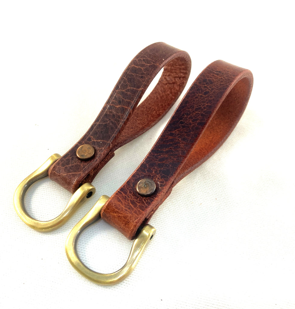 Two brown leather keychains with gold-colored D-rings and buckle closures