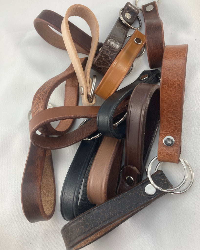A collection of mixed cowhide leather key fobs in various colors with D-ring attachments, designed to hold keys securely.