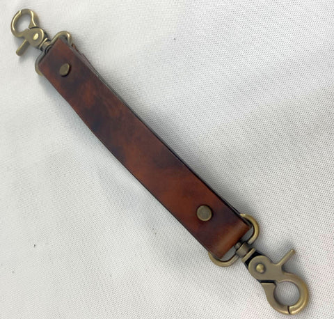 A distressed antique brown leather bag handle with metal snap hooks.